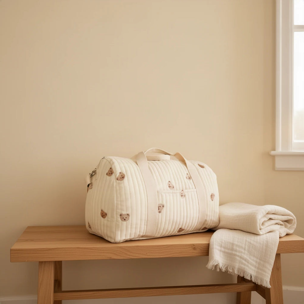 Grand sac à langer en coton matelassé brodé 40 L posé sur un banc dans une entrée