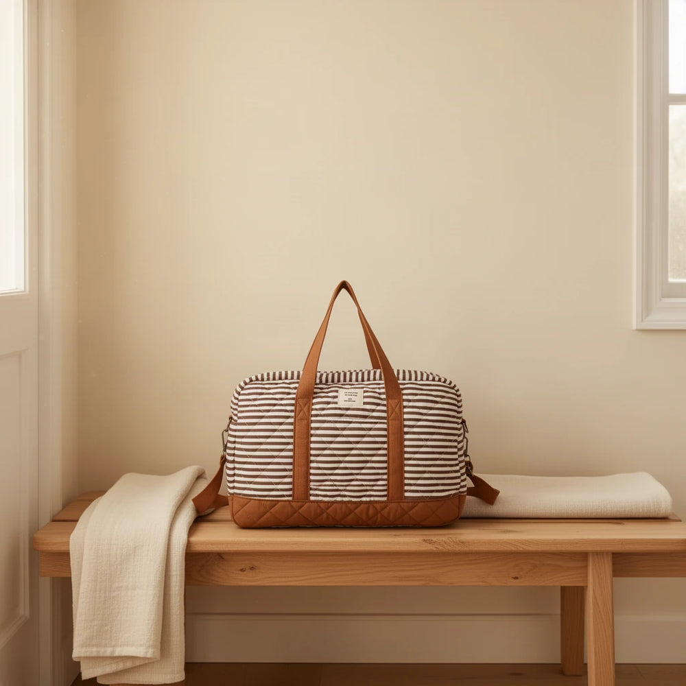 Sac à langer en coton matelassé rayé posé sur un banc dans une entrée