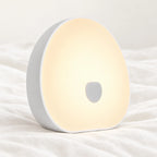 Machine à bruit blanc bébé rechargeable avec veilleuse en gros plan sur un drap blanc