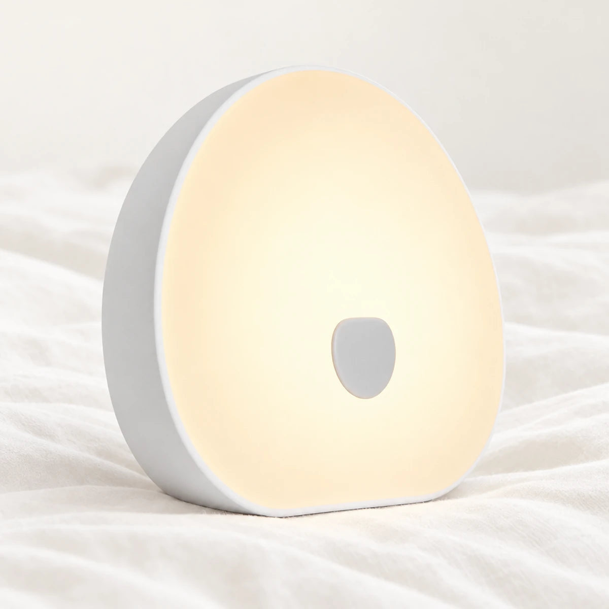 Machine à bruit blanc bébé rechargeable avec veilleuse en gros plan sur un drap blanc