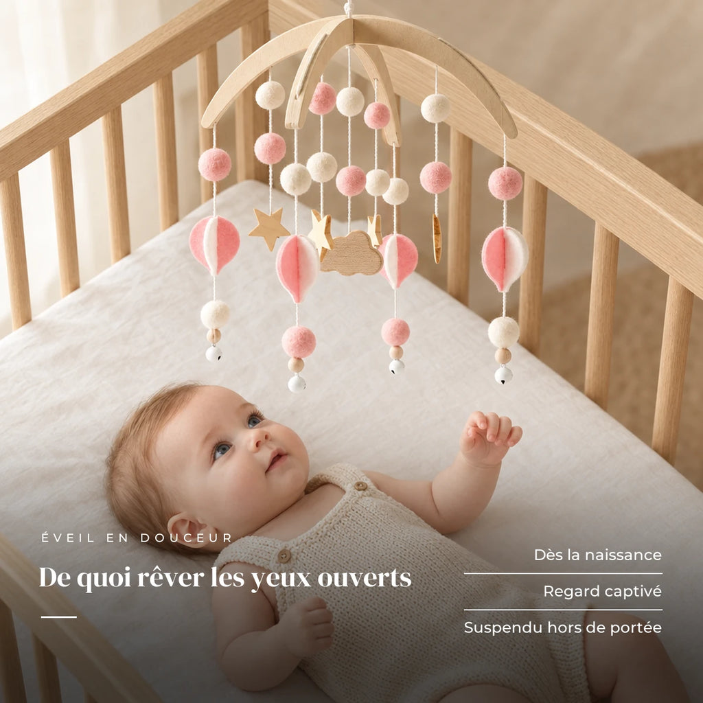 Bébé allongé dans son lit qui regarde le mobile bébé Bohème Rose en bois au-dessus de lui. De quoi rêver les yeux ouverts : dès la naissance, regard captivé, suspendu hors de portée