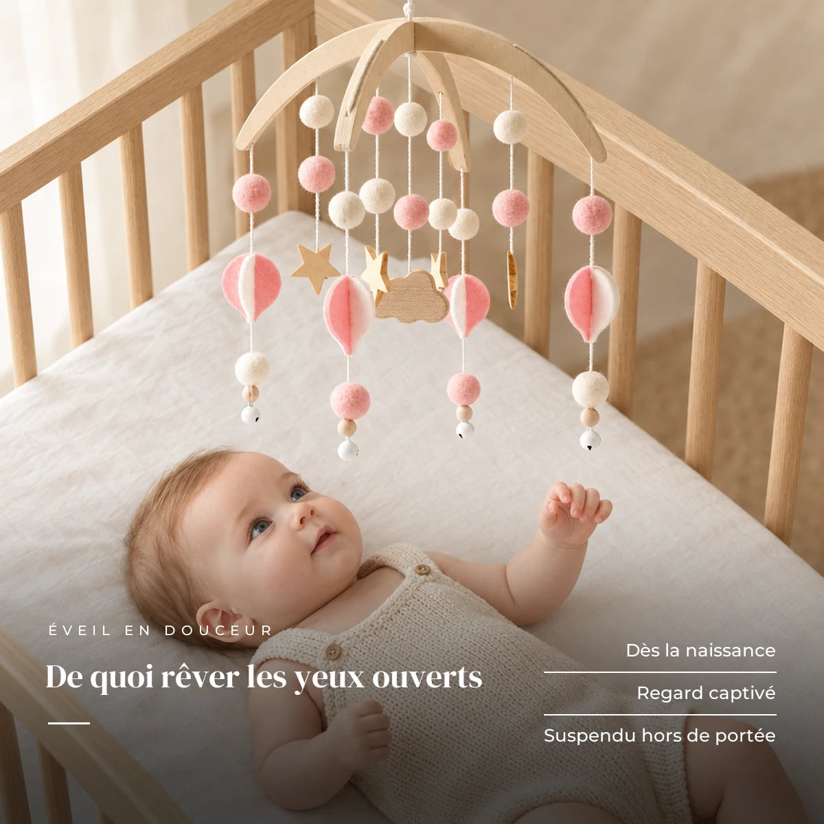 Bébé allongé dans son lit qui regarde le mobile bébé Bohème Rose en bois au-dessus de lui. De quoi rêver les yeux ouverts : dès la naissance, regard captivé, suspendu hors de portée