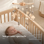 Bébé allongé dans son lit qui regarde le mobile bébé Crépuscule en bois au-dessus de lui. Son premier spectacle : dès la naissance, regard captivé, suspendu hors de portée
