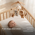 Bébé allongé dans son lit qui regarde le mobile bébé Éléphanteau en bois au-dessus de lui. Il suit chaque mouvement : dès la naissance, regard captivé, suspendu hors de portée