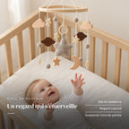 Bébé allongé dans son lit qui regarde le mobile bébé Étoile du berger en bois au-dessus de lui. Un regard qui s’émerveille : dès la naissance, regard captivé, suspendu hors de portée