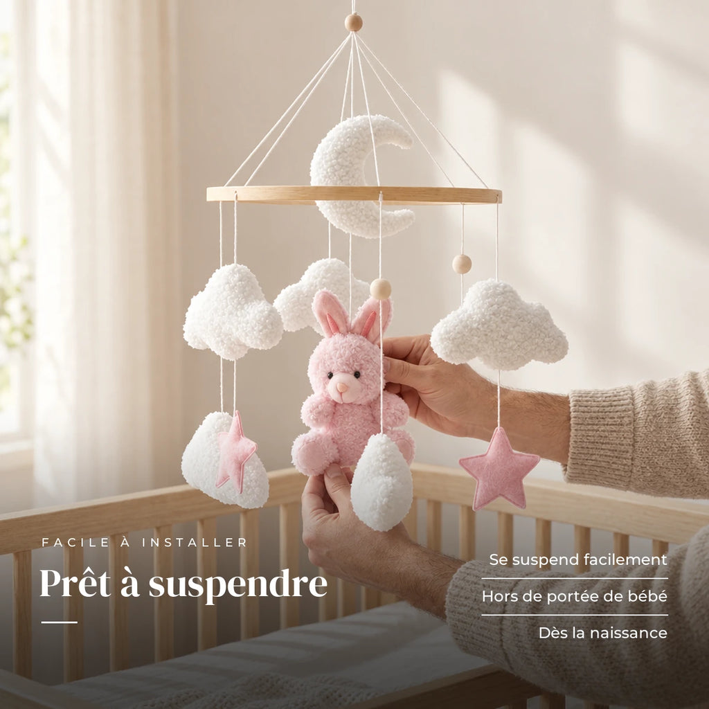 Un parent ajuste une suspension du mobile bébé Lapin rose en bois au-dessus du lit. Prêt à suspendre : se suspend facilement, hors de portée de bébé, dès la naissance