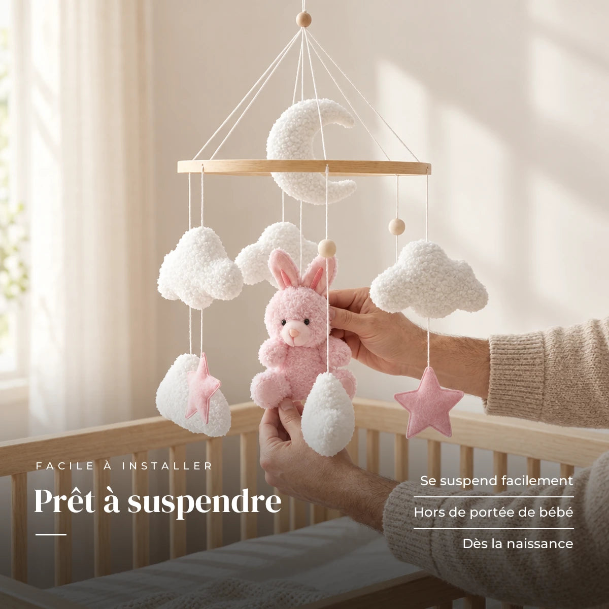 Un parent ajuste une suspension du mobile bébé Lapin rose en bois au-dessus du lit. Prêt à suspendre : se suspend facilement, hors de portée de bébé, dès la naissance