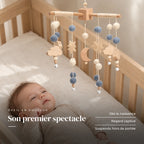 Bébé allongé dans son lit qui regarde le mobile bébé Lune en bois au-dessus de lui. Son premier spectacle : dès la naissance, regard captivé, suspendu hors de portée