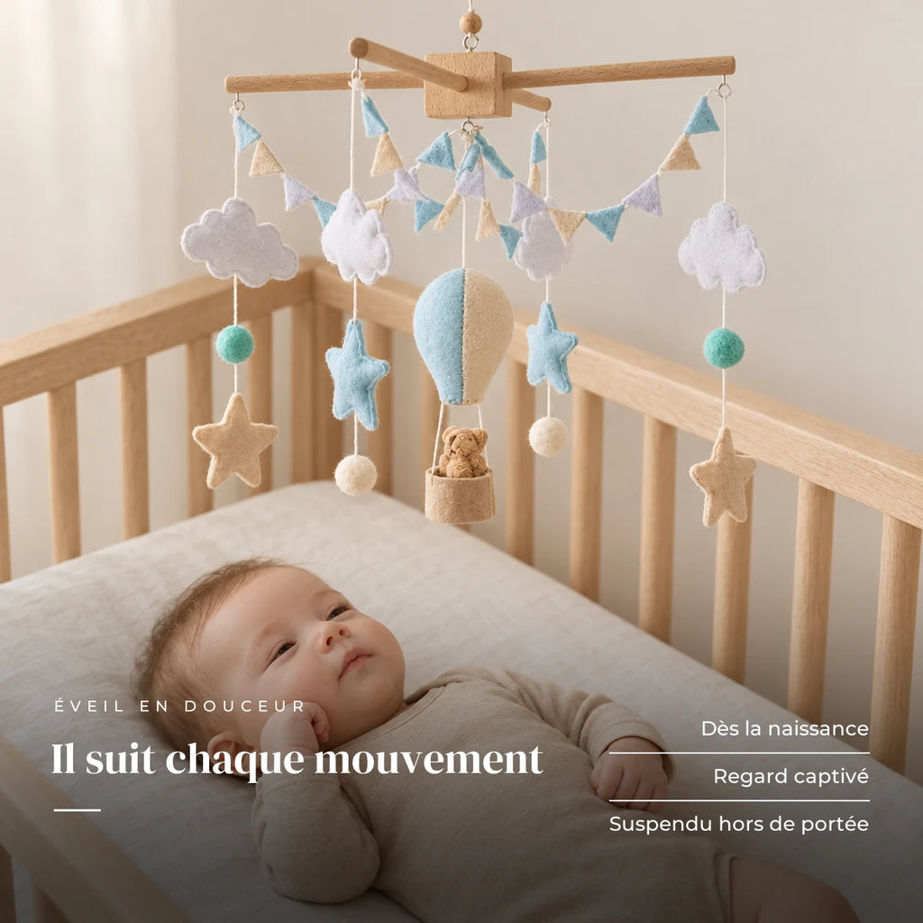 Bébé allongé dans son lit qui regarde le mobile bébé Montgolfière bleue en bois au-dessus de lui. Il suit chaque mouvement : dès la naissance, regard captivé, suspendu hors de portée