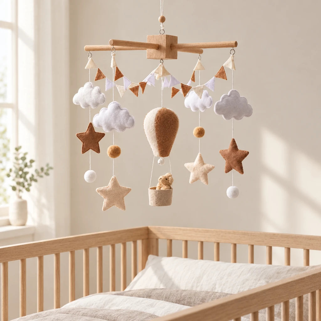 Mobile bébé Montgolfière marron en bois suspendu au-dessus d’un lit bébé en bois clair, dans une chambre douce