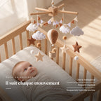 Bébé allongé dans son lit qui regarde le mobile bébé Montgolfière marron en bois au-dessus de lui. Il suit chaque mouvement : dès la naissance, regard captivé, suspendu hors de portée