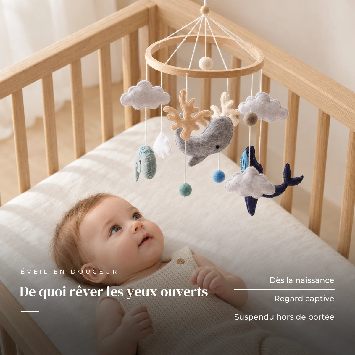 Bébé allongé dans son lit qui regarde le mobile bébé Océan en bois au-dessus de lui. De quoi rêver les yeux ouverts : dès la naissance, regard captivé, suspendu hors de portée