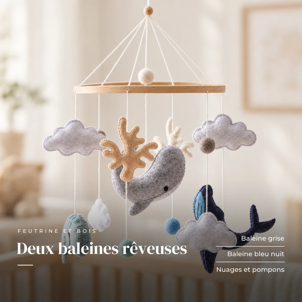 Détail des suspensions du mobile bébé Océan en bois. Deux baleines rêveuses : baleine grise, baleine bleu nuit, nuages et pompons