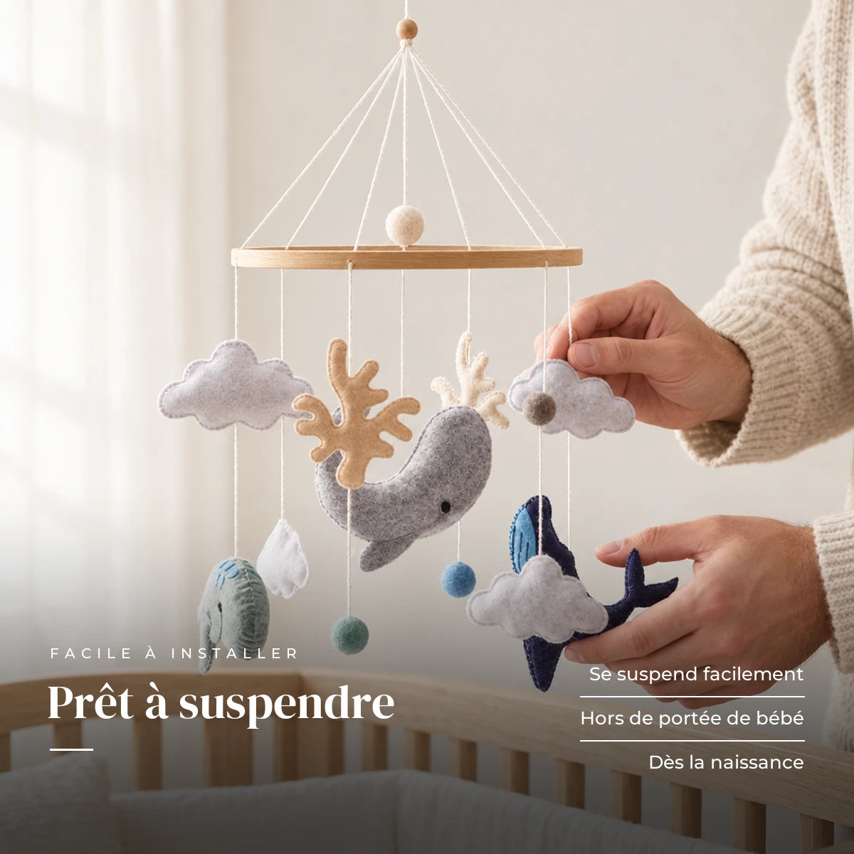 Un parent ajuste une suspension du mobile bébé Océan en bois au-dessus du lit. Prêt à suspendre : se suspend facilement, hors de portée de bébé, dès la naissance