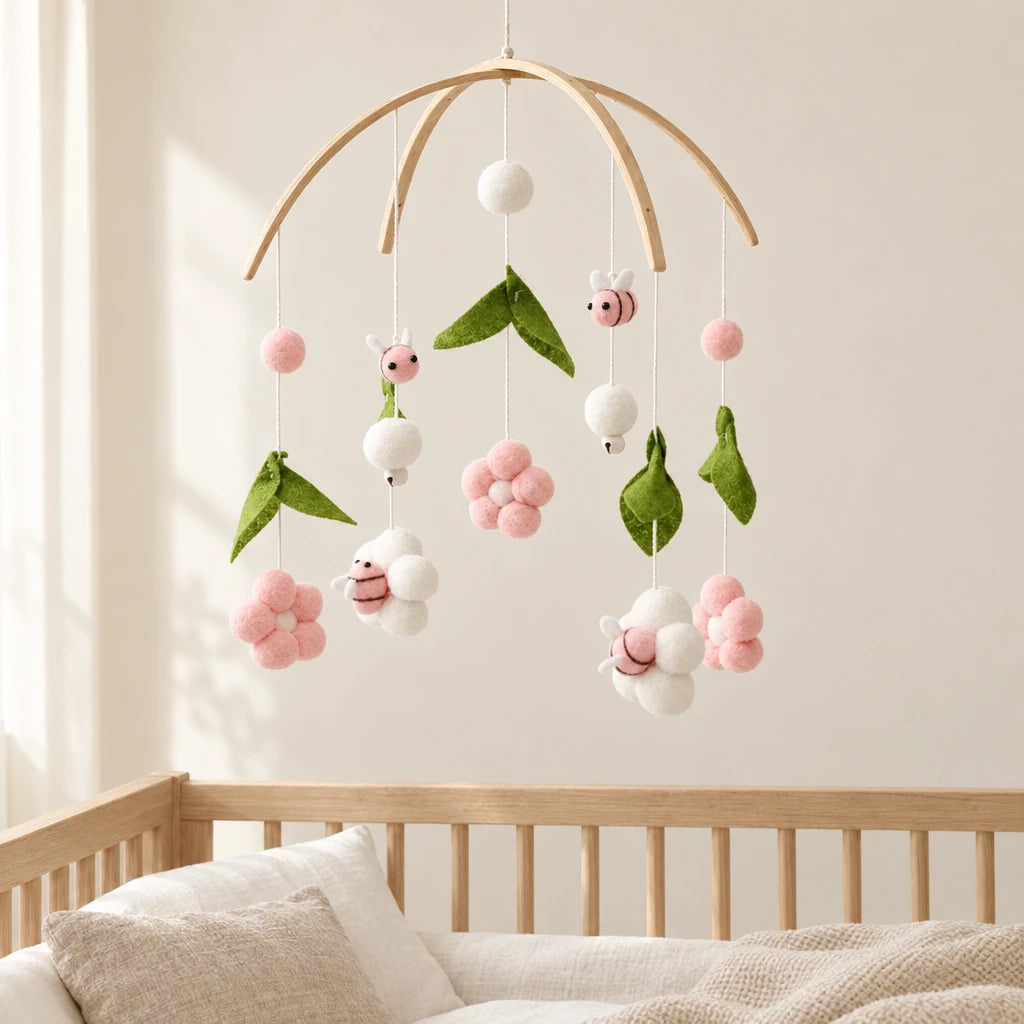 Mobile Bébé Rose Pour Fille en bois suspendu au-dessus d’un lit bébé en bois clair, dans une chambre douce