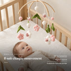 Bébé allongé dans son lit qui regarde le mobile bébé Rose Pour Fille en bois au-dessus de lui. Il suit chaque mouvement : dès la naissance, regard captivé, suspendu hors de portée