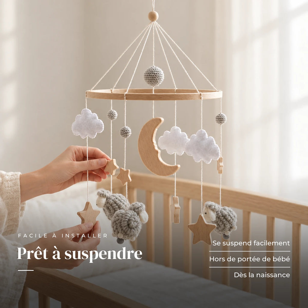 Un parent ajuste une suspension du mobile en bois Moutons gris au-dessus du lit. Prêt à suspendre : se suspend facilement, hors de portée de bébé, dès la naissance
