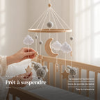 Un parent ajuste une suspension du mobile en bois Moutons gris au-dessus du lit. Prêt à suspendre : se suspend facilement, hors de portée de bébé, dès la naissance