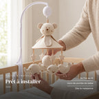 Un parent ajuste une suspension du mobile musical Nounours avec bras au-dessus du lit. Prêt à installer : se fixe au lit, hors de portée de bébé, dès la naissance