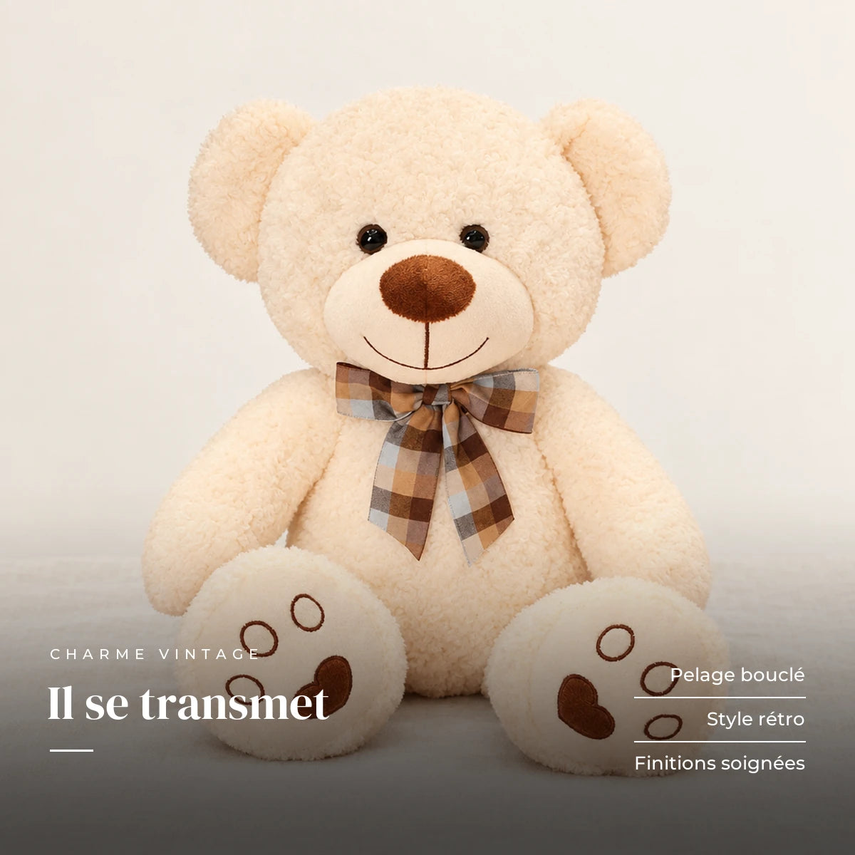Ours en peluche bouclé traditionnel avec nœud rétro beige sur fond crème, en studio. Il se transmet : pelage bouclé, style rétro, finitions soignées
