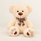 Ours en peluche bouclé traditionnel avec nœud rétro beige sur fond crème, en studio