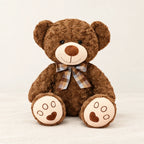 Ours en peluche bouclé traditionnel avec nœud rétro marron sur fond crème, en studio