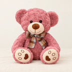 Ours en peluche bouclé traditionnel avec nœud rétro rose sur fond crème, en studio