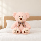 Ours en peluche bouclé traditionnel avec nœud rétro rose pâle posé sur un lit en lin blanc