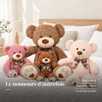 Ours en peluche bouclé traditionnel avec nœud rétro posé sur un lit en lin blanc. Le nounours d’autrefois : pelage bouclé, nœud à carreaux, coussinets brodés