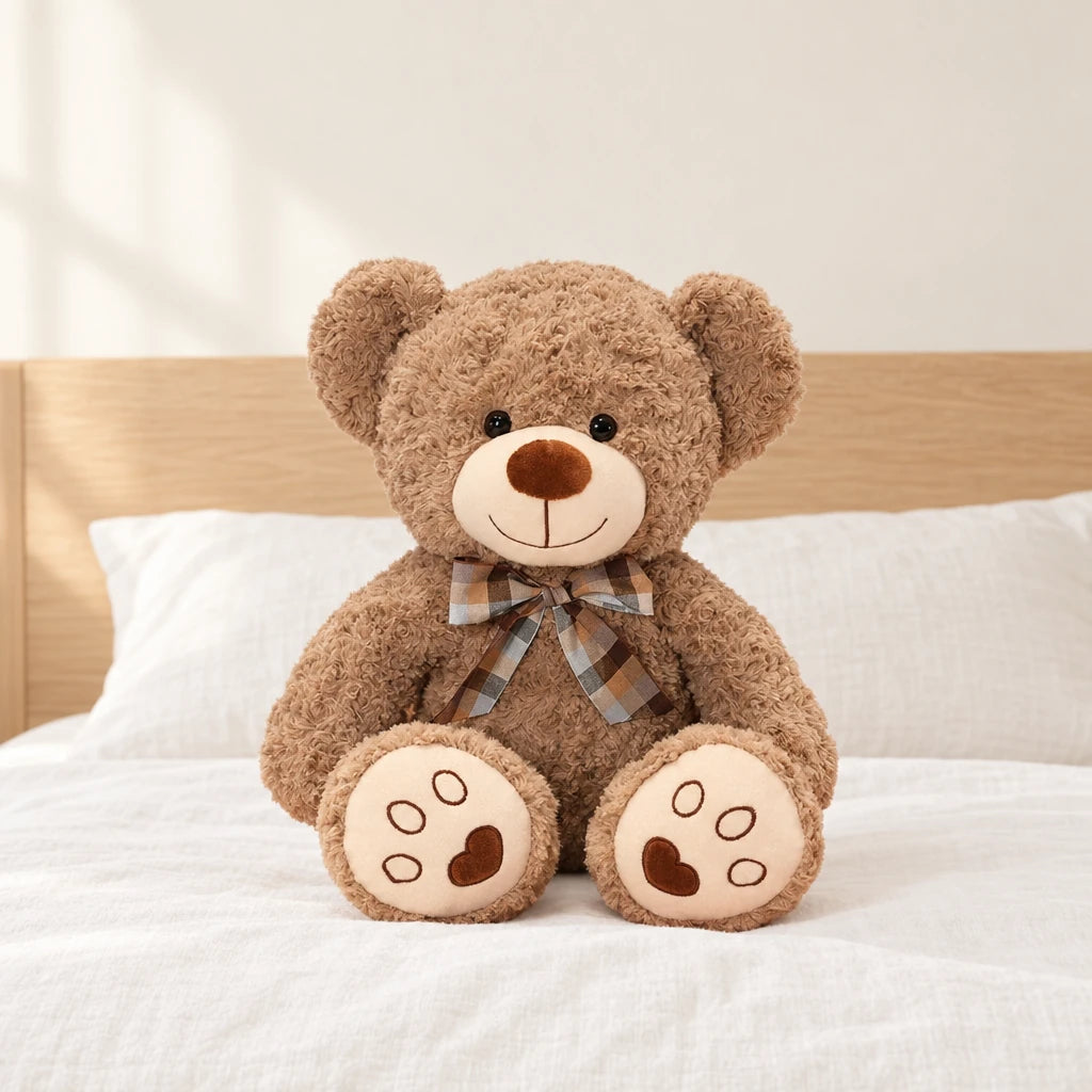 Ours en peluche bouclé traditionnel avec nœud rétro taupe posé sur un lit en lin blanc