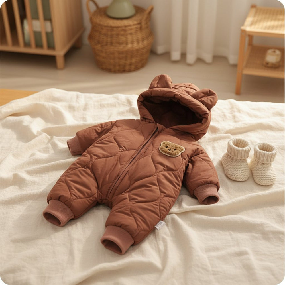 Combinaison Hiver Bébé Aubin, modèle café, posée à plat sur un lit en lin