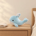 Peluche baleine bleue adorable toute douce posée sur une table de chevet en bois clair