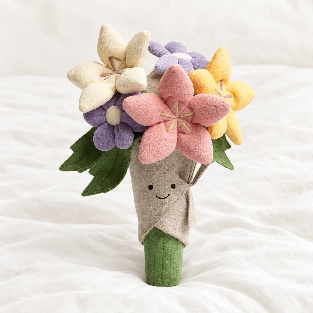 Peluche bouquet de fleurs multicolores kawaii posée sur un lit blanc, en pleine lumière