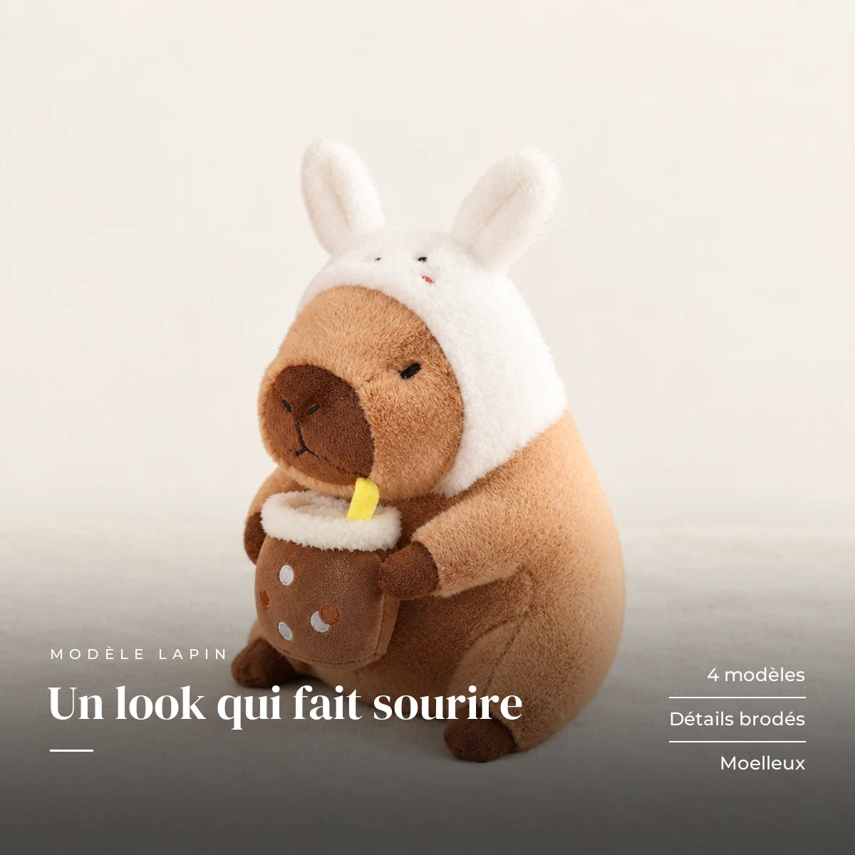 Peluche capybara avec boisson et bonnet rigolo modèle lapin sur fond crème, en studio. Un look qui fait sourire : 4 modèles, détails brodés, moelleux
