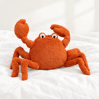 Peluche crabe tout doux posée sur un lit blanc, en pleine lumière