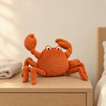 Peluche crabe tout doux posée sur une table de chevet en bois clair