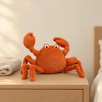 Peluche crabe tout doux posée sur une table de chevet en bois clair