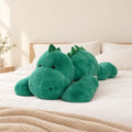 Peluche dinosaure géant relax posée sur un lit en lin blanc