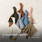 Peluche doudou oie pour bébé en coton présentée à plat sur du lin crème. Le doudou qui va partout : coton doux, forme plate, dès la naissance
