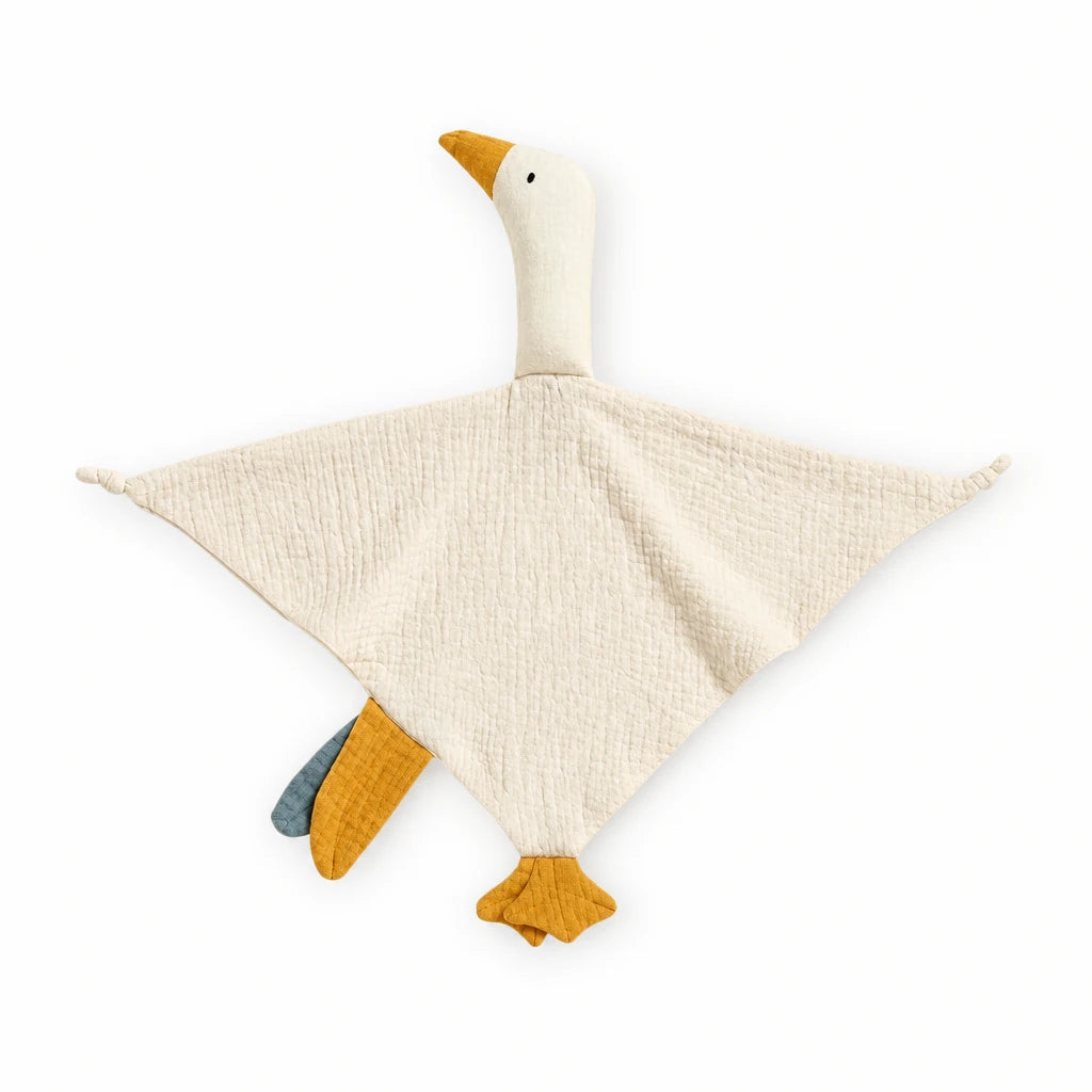 Peluche doudou oie pour bébé en coton posée sur un lit blanc, en pleine lumière