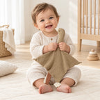 Peluche doudou oie pour bébé en coton taupe dans les bras d’un bébé éveillé