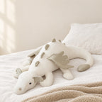 Dragon en peluche aux couleurs pastel blanc posé sur un lit en lin blanc