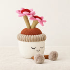 Peluche kawaii fleurs en pot de terre sur fond crème, en studio
