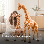 Peluche géante girafe dans les bras d’un adulte. Les fans d’animaux craquent : grande taille, coton doux, pelage tacheté