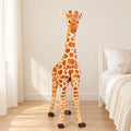 Peluche géante girafe posée sur un lit en lin blanc