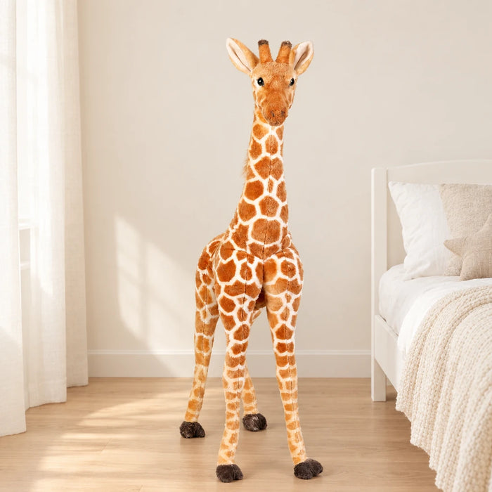 Peluche géante girafe posée sur un lit en lin blanc