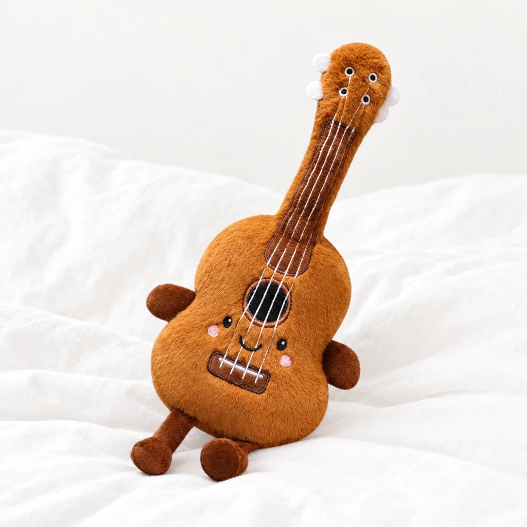 Peluche instrument kawaii guitare souriante posée sur un lit blanc, en pleine lumière