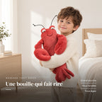 Peluche homard tout doux avec un enfant dans une chambre lumineuse. Une bouille qui fait rire : grand sourire, yeux brodés, tous âges