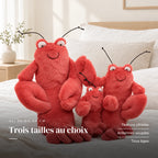 Peluche homard tout doux posée sur un lit en lin blanc. Trois tailles au choix : texture côtelée, antennes souples, tous âges
