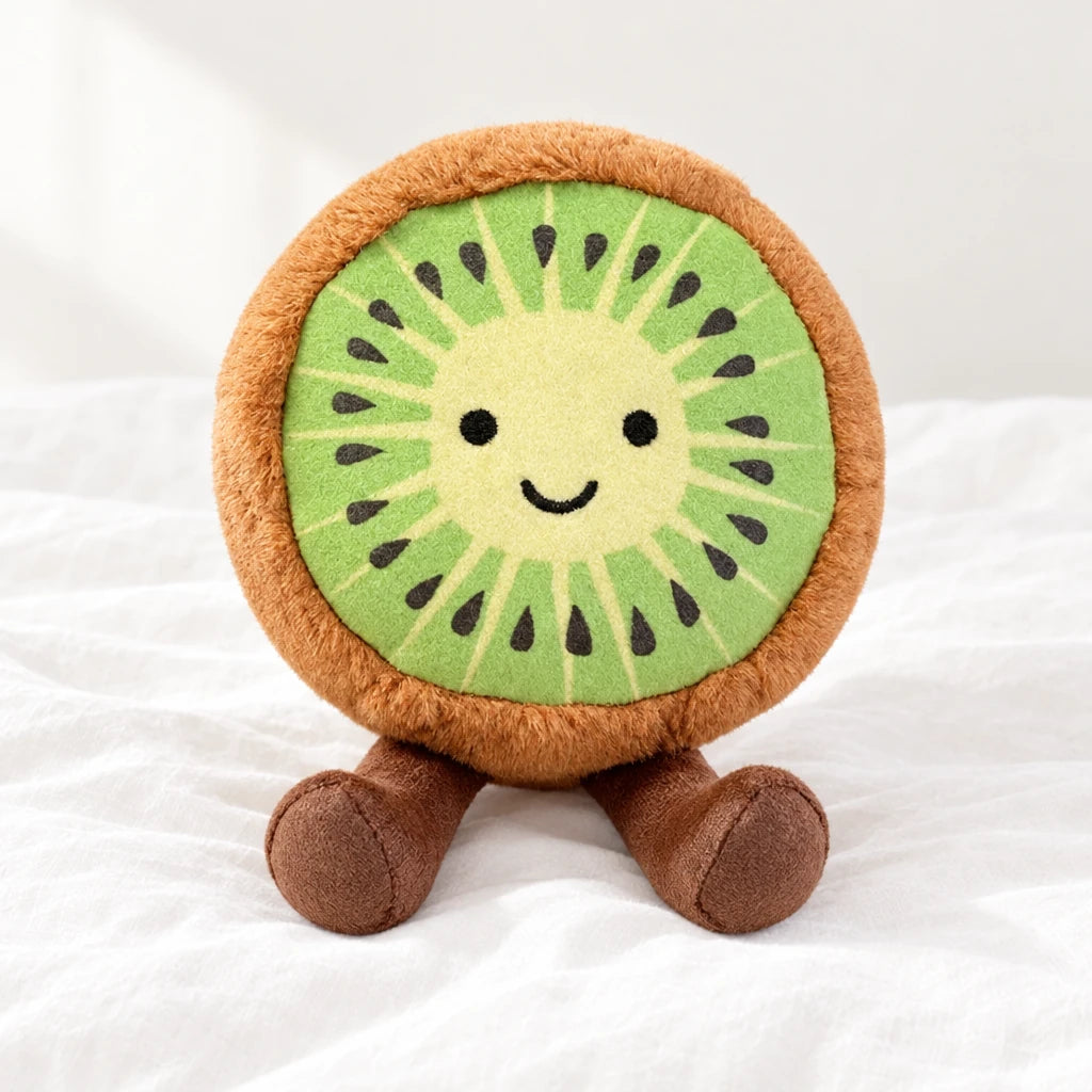 Peluche fruit kawaii kiwi joyeux posée sur un lit blanc, en pleine lumière